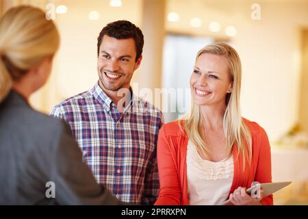 Prendere decisioni responsabili sul loro futuro. Una coppia felice che scuote le mani con il loro consulente finanziario nella loro casa. Foto Stock