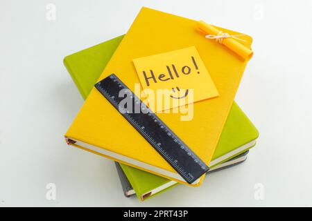 vista dal basso ciao scritto su righello per appunti appiccicosi su quaderni colorati su sfondo bianco Foto Stock