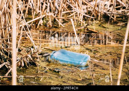 Vecchia Tanica in plastica galleggia in acqua di palude o stagno. Utilizzato vuoto materiali di imballaggio a sinistra in acqua. Concetto di Eco Garbage disastro da Pollut ecologico Foto Stock