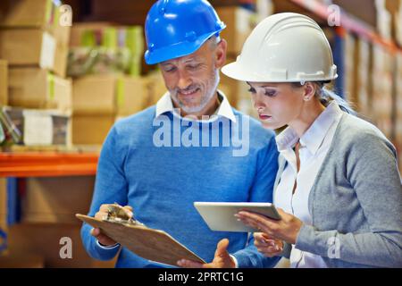 Permettetemi di mostrarvi come ho ottenuto questa cifra: Due persone che fanno un controllo dell'inventario in un magazzino. Foto Stock