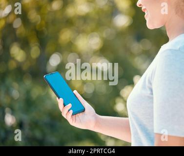 Passeggiata nella natura per donna con telefono mockup per la tranquillità, la sana mentalità o la libertà con schermo blu croma key. Ragazza con uno spazio fotocopie per smartphone che cammina nel parco all'aperto per il benessere o l'esercizio fisico Foto Stock