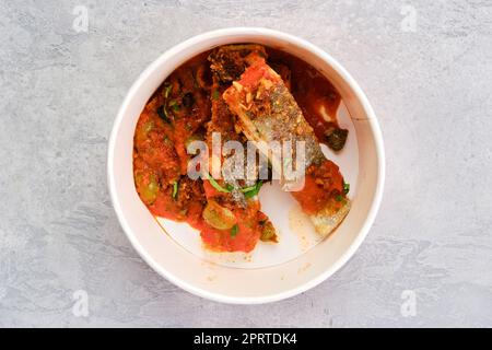 Vista dall'alto dello zander arrosto servito con pomodoro al vapore, cipolla e salsa di olive Foto Stock