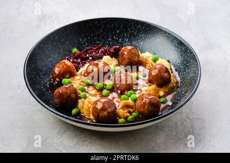 Polpette con sugo di carne servite con purè di patate, piselli verdi e marmellata di mirtilli Foto Stock