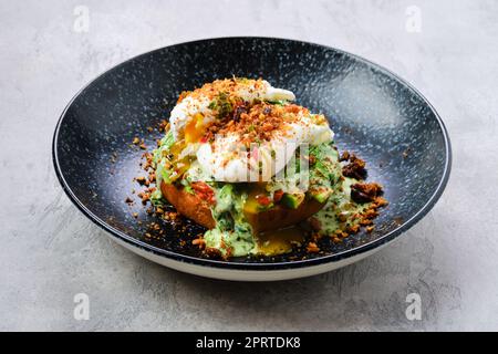 Uovo in camicia su un panino con avocado Foto Stock