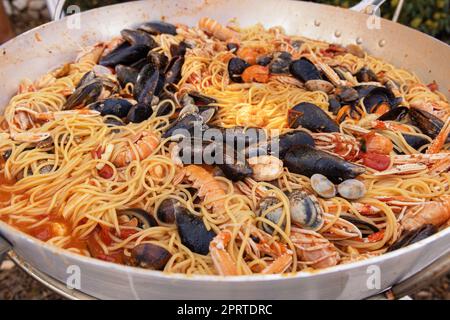 Spaghetti italiani allo scoglio, primi piani di pasta con frutti di mare e pomodori in padella Foto Stock