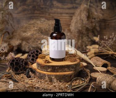 Una bottiglia cosmetica su legno vicino alle decorazioni boho naturali da vicino. Etichetta Mockup Foto Stock