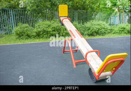 Altalena a forma di tavola di legno in un parco giochi vuoto all'aperto, area giochi per bambini Foto Stock