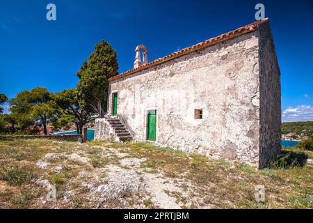 Antica cappella in pietra sulla collina sopra la città di Tisno, isola Murter di Croazia Foto Stock