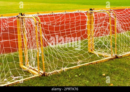 Piccoli goal di calcio si sono allineati accanto a una pista da corsa Foto Stock