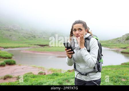 Spaventato l'escursionista perso che controlla lo smartphone in montagna Foto Stock