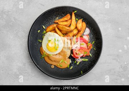 Vista dall'alto del controfiletto di maiale tritato con spicchi di patate fritti, uova, pomodoro e ravanelli Foto Stock