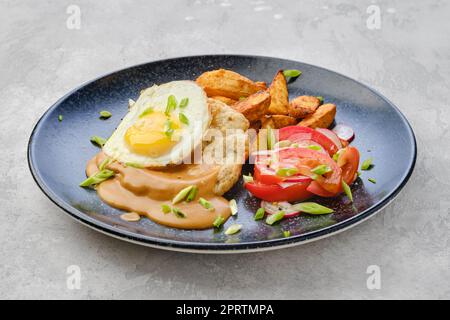 Controfiletto di maiale tritato con spicchi di patate fritti, uova, pomodoro e ravanello Foto Stock