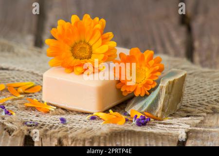 Sapone naturale fatto a mano con calendula (vasetto marigold) su fondo rustico in legno Foto Stock