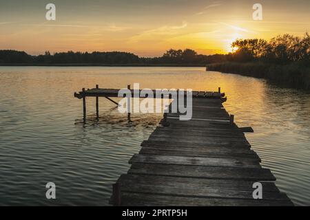 Tramonto su un lago tranquillo con un molo Foto Stock