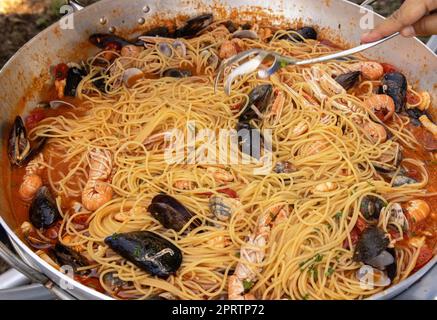 Spaghetti italiani allo scoglio, primi piani di pasta con frutti di mare e pomodori in padella Foto Stock