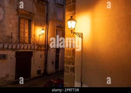 Due vecchie lampade di strada brillano di notte nei vicoli storici del centro storico di Palermo. Foto Stock