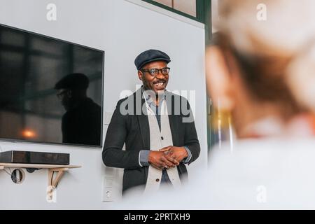 Un uomo d'affari sorridente durante un incontro con i colleghi in ufficio Foto Stock