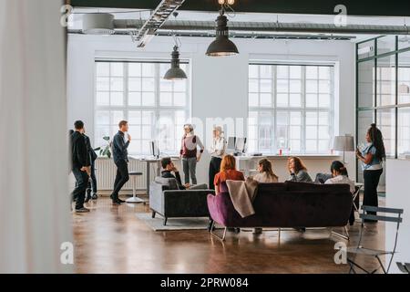 Uomini d'affari e donne che discutono tra loro in un posto di lavoro moderno Foto Stock