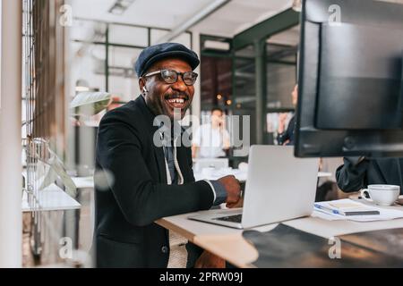 Buon uomo d'affari maturo che indossa cuffie intrauricolari wireless seduti in ufficio con un computer portatile Foto Stock