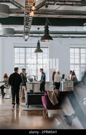 Uomini d'affari e donne che discutono l'uno con l'altro in un ufficio moderno Foto Stock