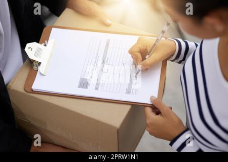 Un altro pacchetto è stato consegnato correttamente. una giovane donna che firma per il suo pacchetto dal corriere Foto Stock