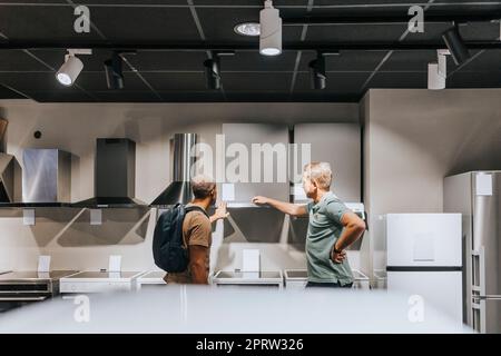 Venditore che consiglia al cliente maschio di acquistare apparecchi presso un negozio di elettronica Foto Stock