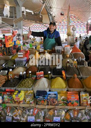 Fornitore di spezie dietro il suo stand in bazar Chorsu a Tashkent, Uzbekistan Foto Stock