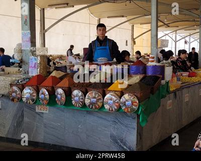 Fornitore di spezie dietro il suo stand in bazar Chorsu a Tashkent, Uzbekistan Foto Stock