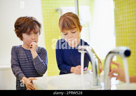 Spazzolando prima di andare a letto, un fratello e una sorella si lavano i denti a casa. Foto Stock