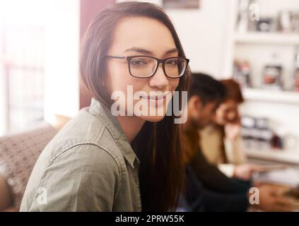 Tutti abbiamo bisogno di un po' di tempo. Ritratto di una giovane donna in una caffetteria con i suoi amici seduti sullo sfondo. Foto Stock