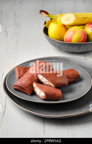 Sottili pancake al cioccolato ripieni di ricotta banana e mela Foto Stock