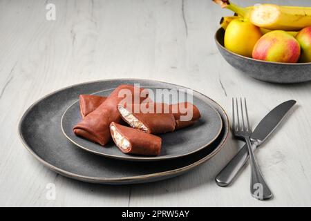 Sottili pancake al cioccolato ripieni di ricotta banana e mela Foto Stock