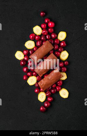 Composizione a soffitto con sottili pancake al cioccolato ripieni di formaggio cottage, ciliegia e banana Foto Stock