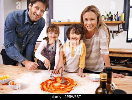 Facciamo sempre la nostra pizza. Una famiglia che fa la pizza insieme a casa. Foto Stock