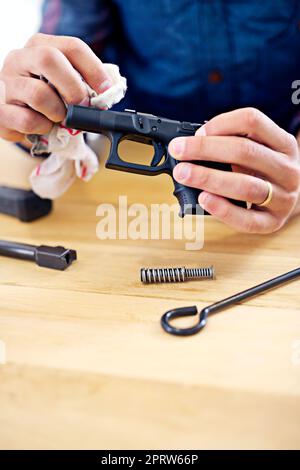 La manutenzione regolare è essenziale per ogni proprietario di pistola. Vista ritagliata di un uomo che pulisce la sua pistola. Foto Stock