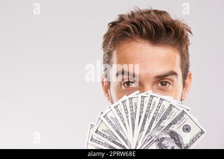 Ive ha ottenuto i soldi da risparmiare. Studio shot di un uomo d'affari che tiene un ventilatore di soldi davanti al suo volto. Foto Stock