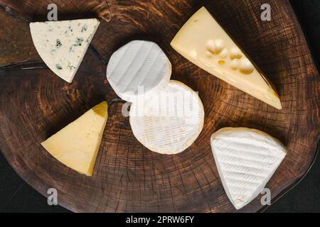 Vista dall'alto dell'assortimento di formaggio brie, camembert, parmigiano e gouda su tagliere di legno. Foto Stock