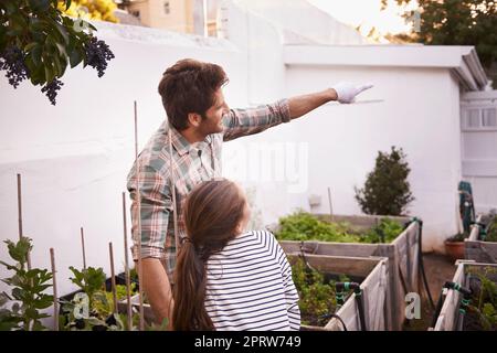 La sua bambina condivide il suo amore per il giardinaggio: Un padre e una figlia che si trovano nel giardino del cortile. Foto Stock