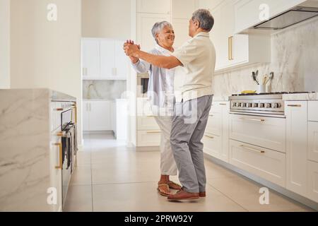 Ballo di coppia, cucina e amore per le persone anziane che trascorrono momenti di qualità insieme a casa. Felice pensionamento di una donna e di un uomo messicano che ballano in casa loro con un sorriso e una felicità Foto Stock