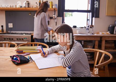 In cima alla sua classe... Una giovane ragazza impegnata che fa i compiti a casa al tavolo da cucina. Foto Stock