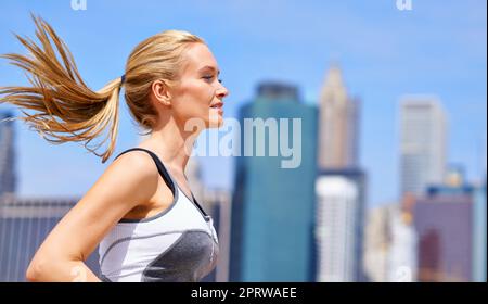 Godendo la città in cui vive a piedi. Una bella donna bionda fuori per una corsa in città. Foto Stock