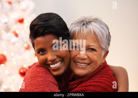 Tempo di qualità a Natale. Una donna anziana che riceve un abbraccio da sua figlia il Natale. Foto Stock