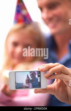 Momenti da ricordare. Un taglio corto di un uomo felice che scatta una foto di se stesso e della sua figlia in occasione del suo compleanno. Foto Stock