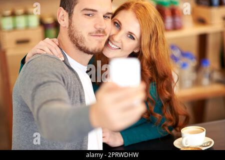 Mostrare la sua data calda. Una giovane coppia che scatta una foto di se stessi mentre si è in un appuntamento in un bar. Foto Stock