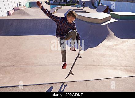 HES ha stile. Un giovane che fa trucchi sul suo skateboard al parco skate. Foto Stock