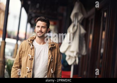 Domenica mattina passeggiando, un giovane felice che cammina per la strada. Foto Stock