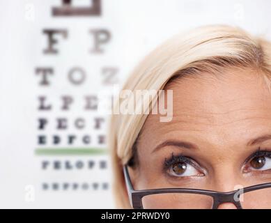 Vista per occhi irritati. Un taglio corto di un bellissimo optometrista davanti a una carta snellen. Foto Stock