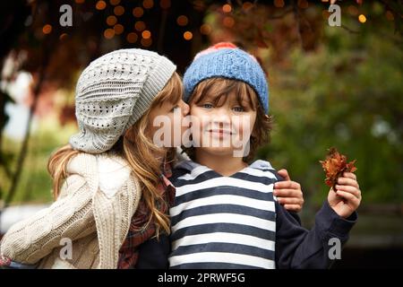 Nessuna rivalità di fratelli qui. Una bambina carina che dà al fratello un bacio sulla guancia. Foto Stock