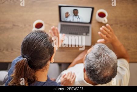 Coppia anziana con un computer portatile in videochiamata con un medico per consultazione durante il periodo di confinamento sopra. Uomo e donna parlano, onda e telesalute con medico esperto di assistenza sanitaria per consultare sulla salute a casa Foto Stock