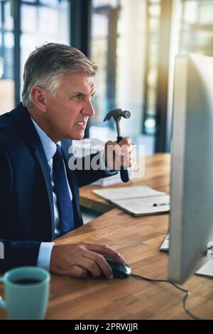 Tempo necessario per una reimpostazione a freddo. un uomo d'affari frustrato che minaccia di colpire lo schermo del suo computer con un martello Foto Stock